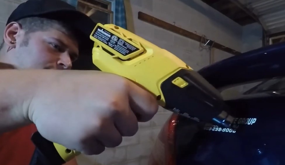 A guy using heat to scrap of window sticker