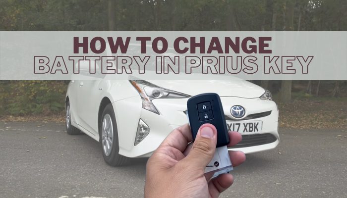 Hand holding a Toyota Prius key fob in front of a white Prius