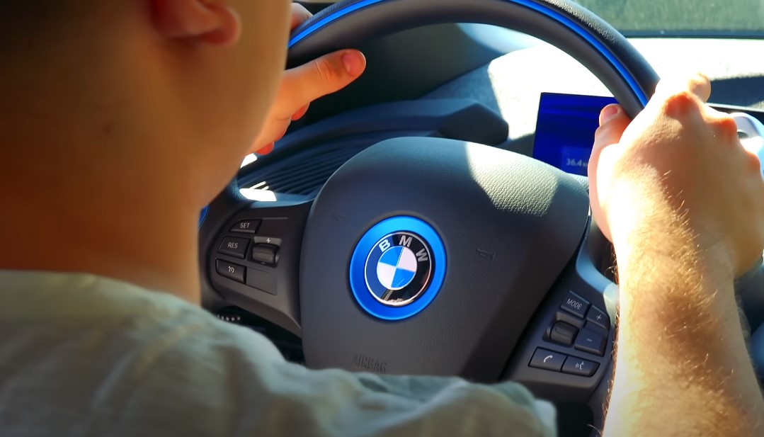 Guy holding a BMW steering wheel while driving