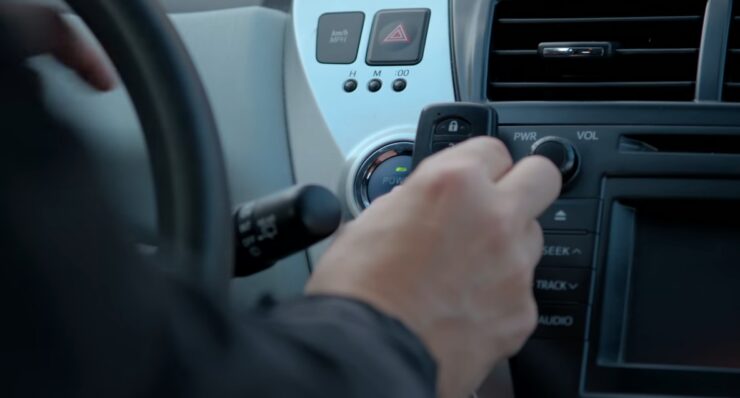 Person holding a Toyota key fob near the car's dashboard, preparing to use it to start the vehicle or operate the controls