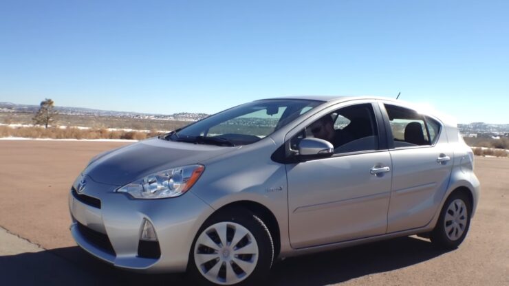 Silver Toyota Prius C parked outdoors on a clear sunny day, showcasing the compact hybrid hatchback's exterior design