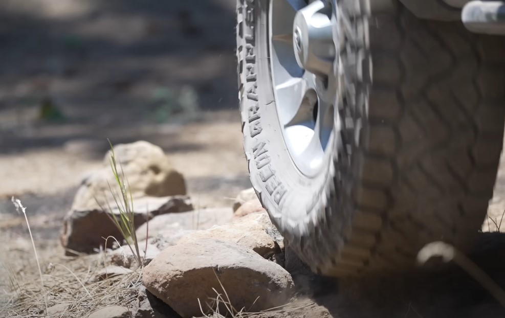 A close up photo of a truck tire running over a rock