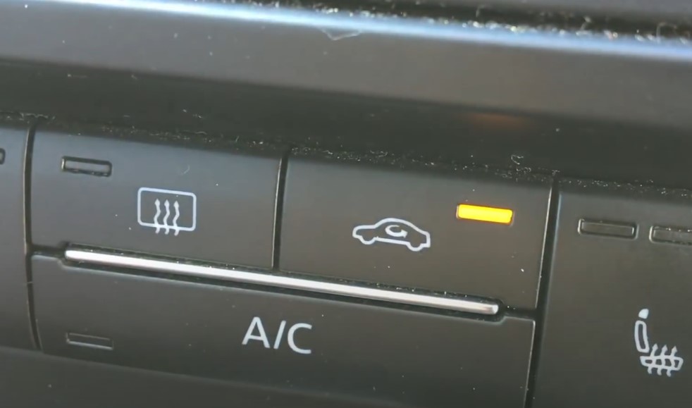 A close up photo of the A/C button in a car