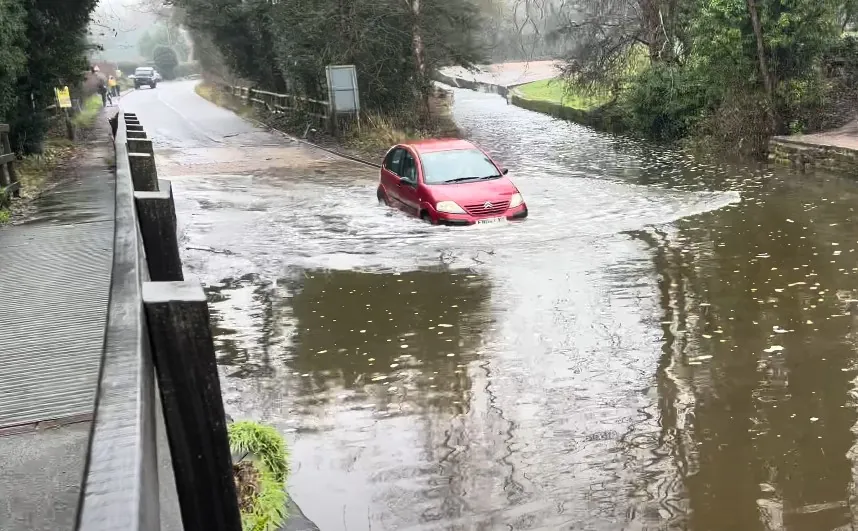 Red car drives through flooded road