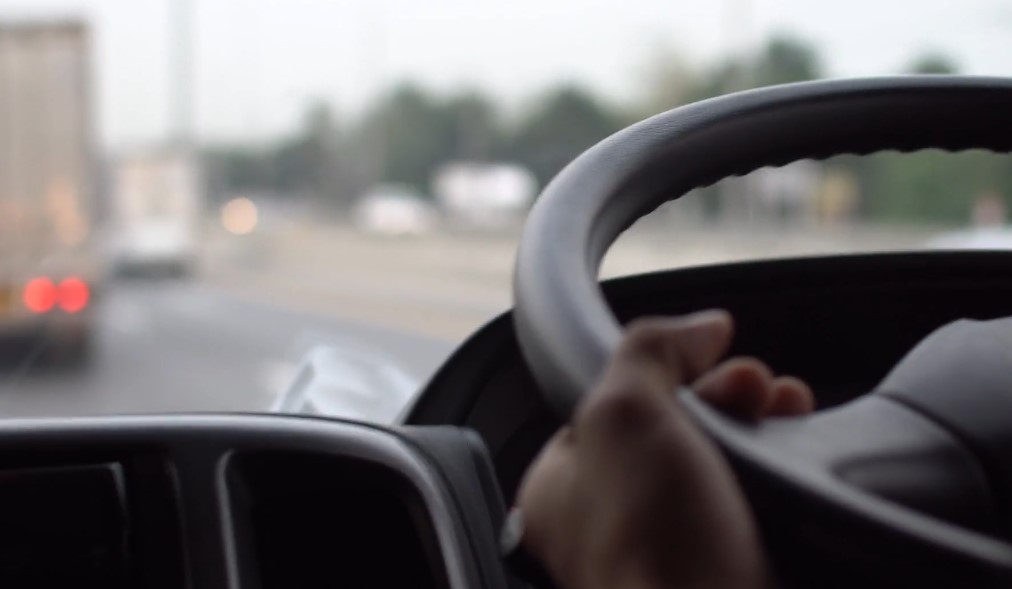 Close up photo of a truck driver's hand on a steering wheel