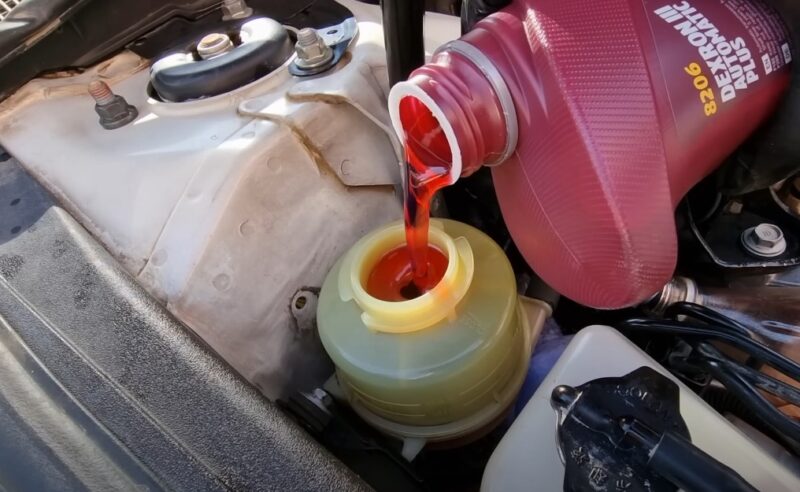 Red coolant is being poured into a reservoir