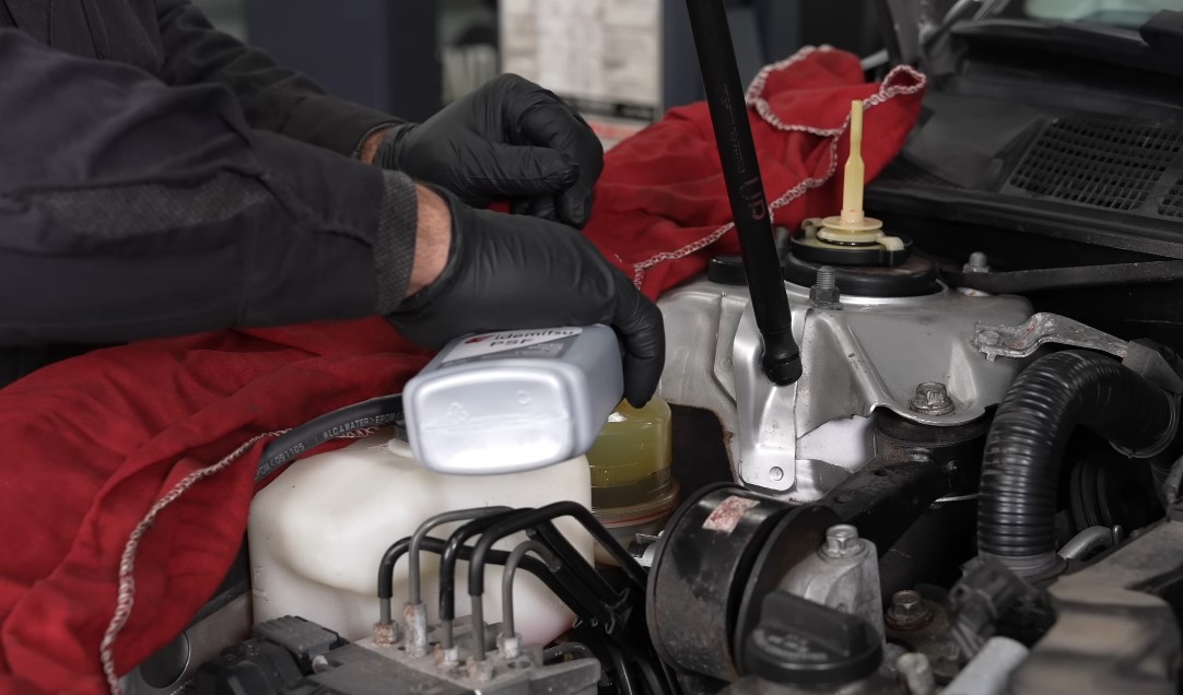 Mechanic changing fluid under the hood