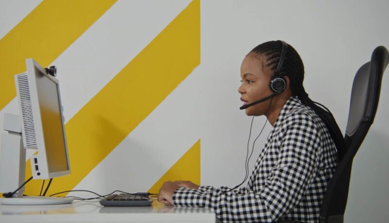 A customer service representative attentively listens to a client on a headset