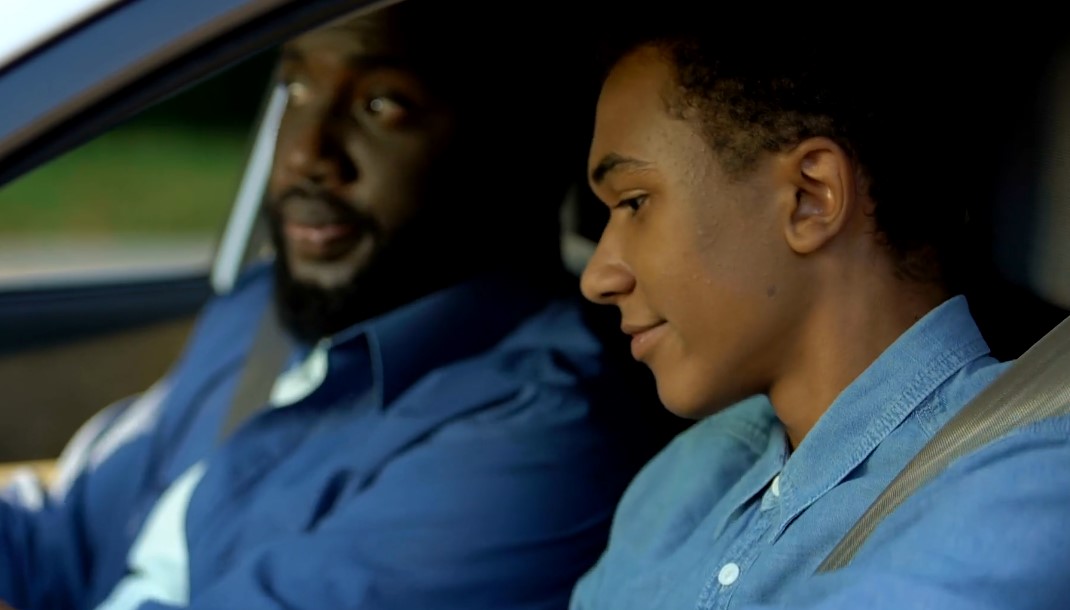 A father guides his son through the process of learning to drive