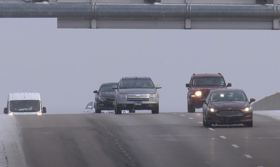 Motor vehicles move along a highway during a bad weather