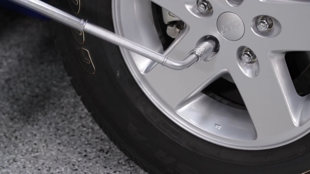 A man torquing wheel lug nuts on a Jeep Wrangler