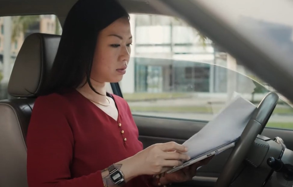 A woman reviews paperwork in a car