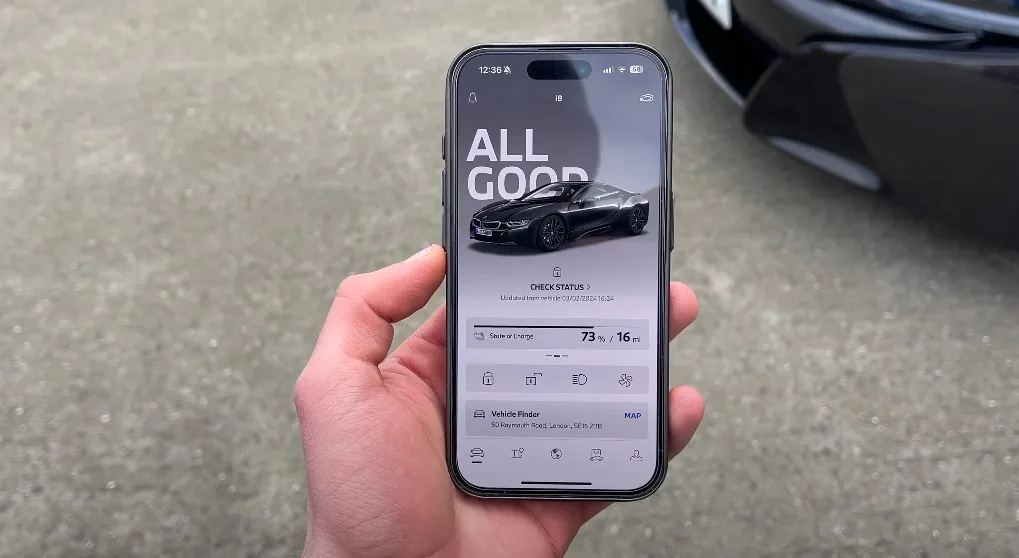 A person holds phone with car app interface on it