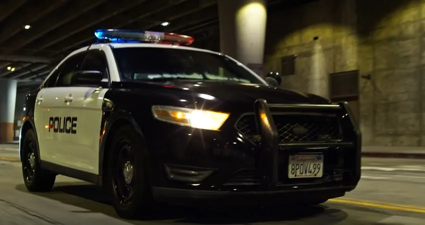 A patrol car, lights flashing, navigating a city underpass