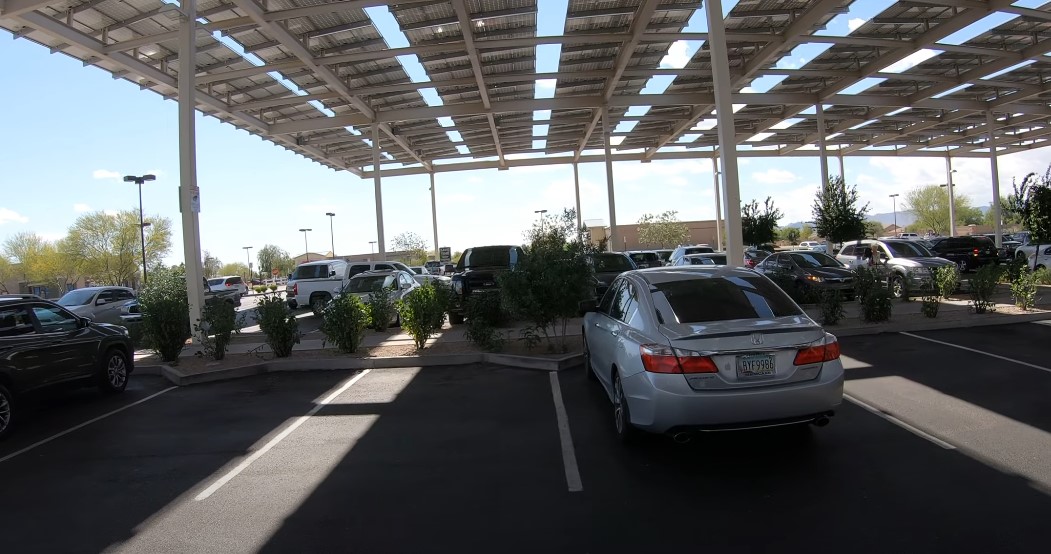 A parking lot under a solar-powered canopy, showcasing a variety of vehicles