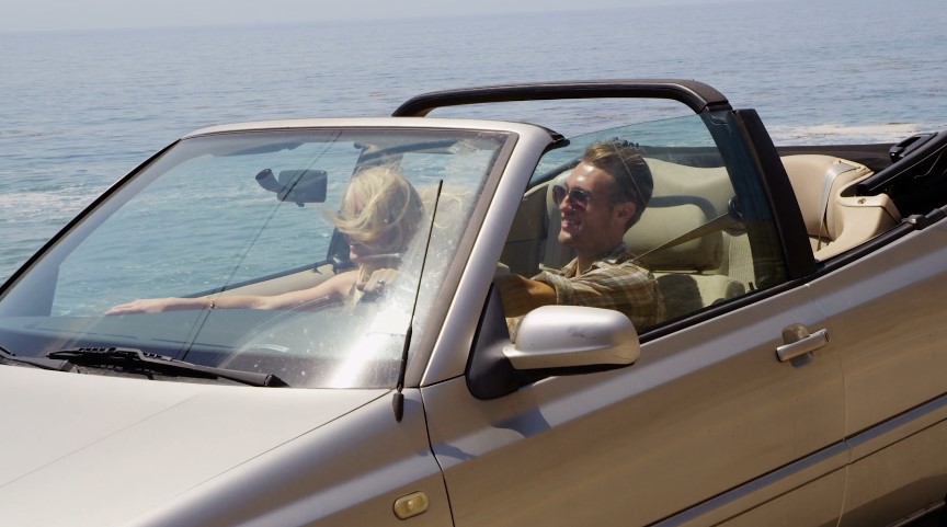 Couple enjoying a convertible car ride along the coast