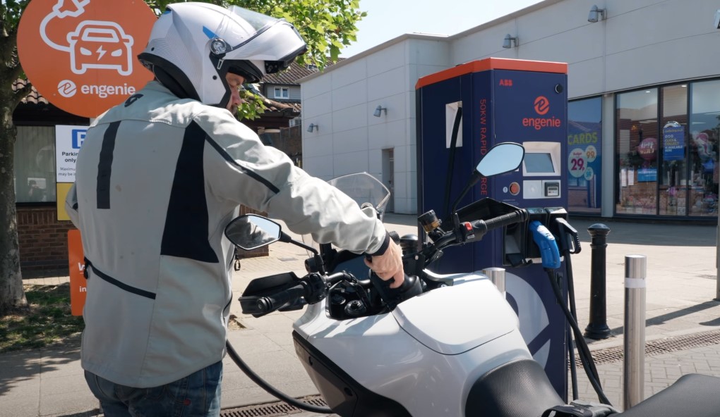 A man wearing a helmet charging his electric motorcycle