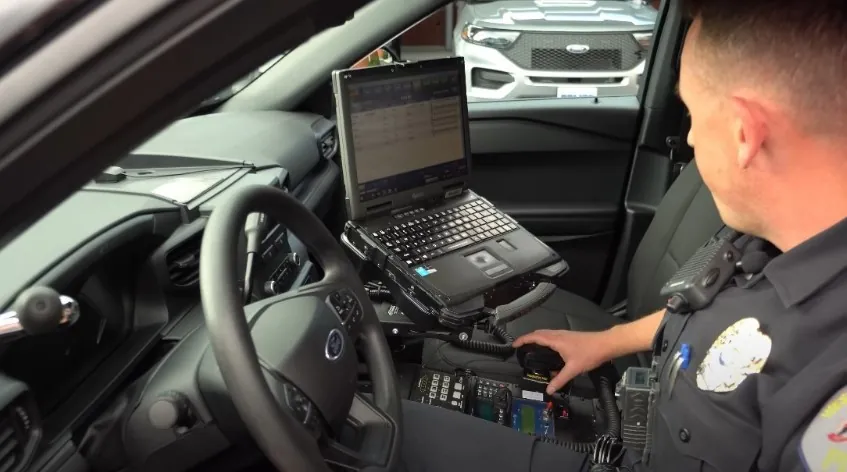 Officer in a patrol vehicle, reviewing information on a laptop