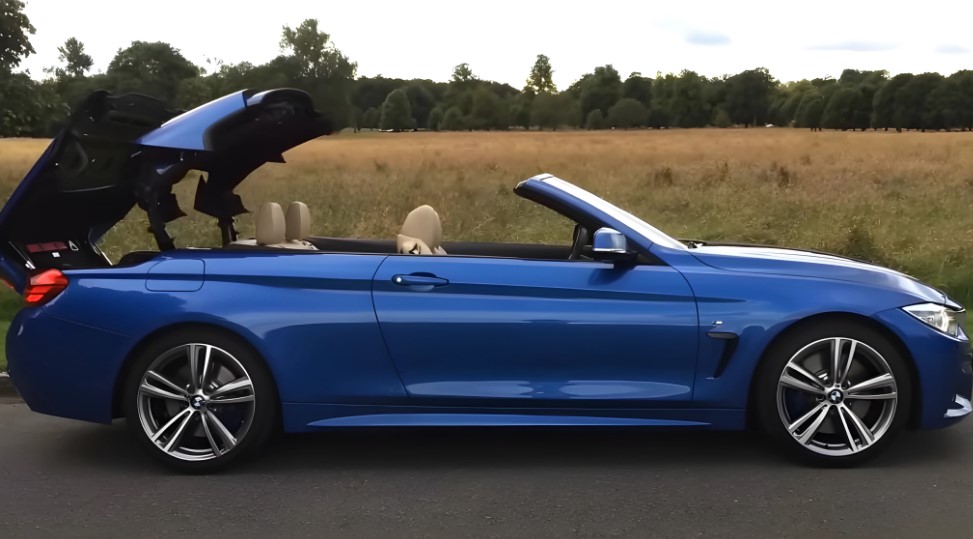 A blue convertible, top down, parked amidst a golden field