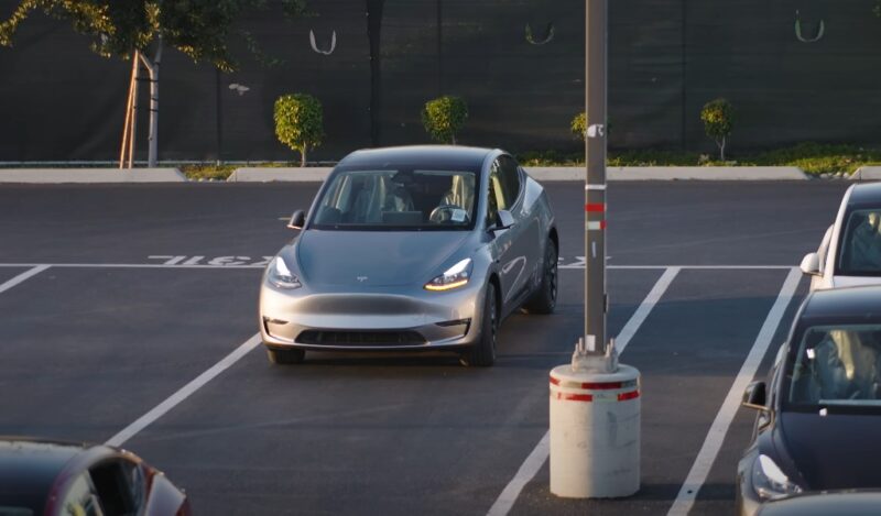 A sleek, silver Tesla Model Y sits parked in a parking lot