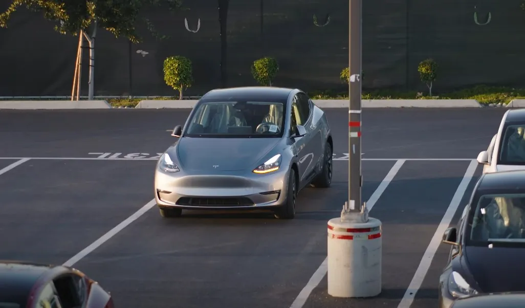 A sleek, silver Tesla Model Y sits parked in a parking lot