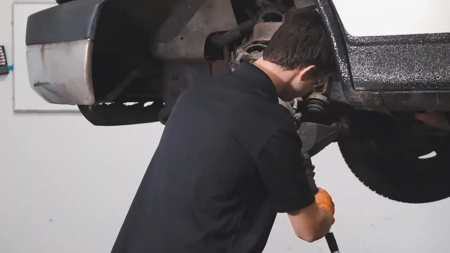 A mechanic inspects a vehicle's undercarriage