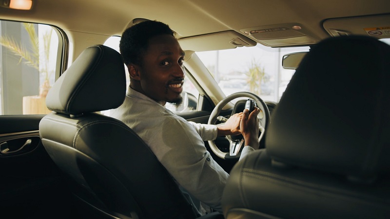 Happy car owner sitting in the driver's seat looking back