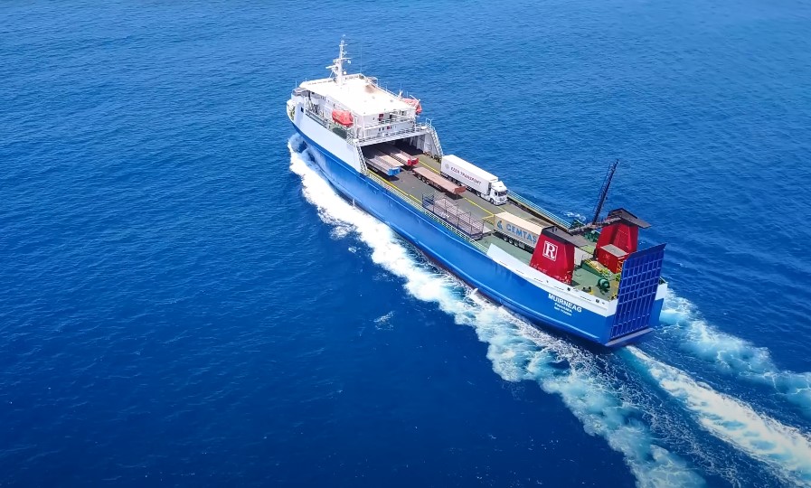 A large blue cargo ship navigates through the ocean