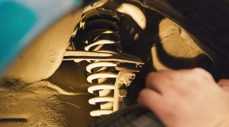 Close-up view of a car's suspension system, showcasing the coil spring and shock absorber