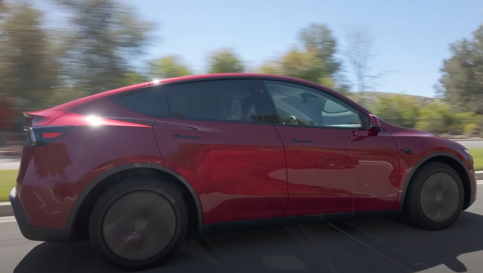A red Tesla Model Y electric vehicle glides smoothly down the road