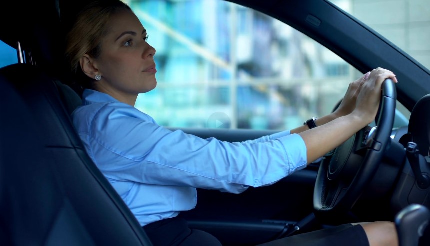 Focused driver in a light blue shirt, hands firmly on the steering wheel
