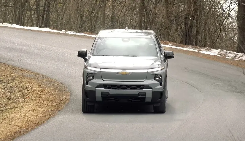 A light gray Chevrolet Silverado EV navigates a winding road