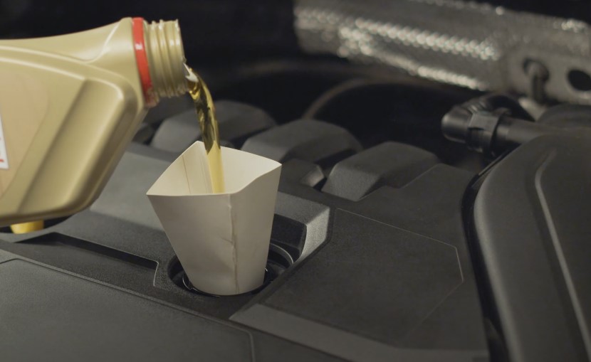 A person pouring oil into a car engine