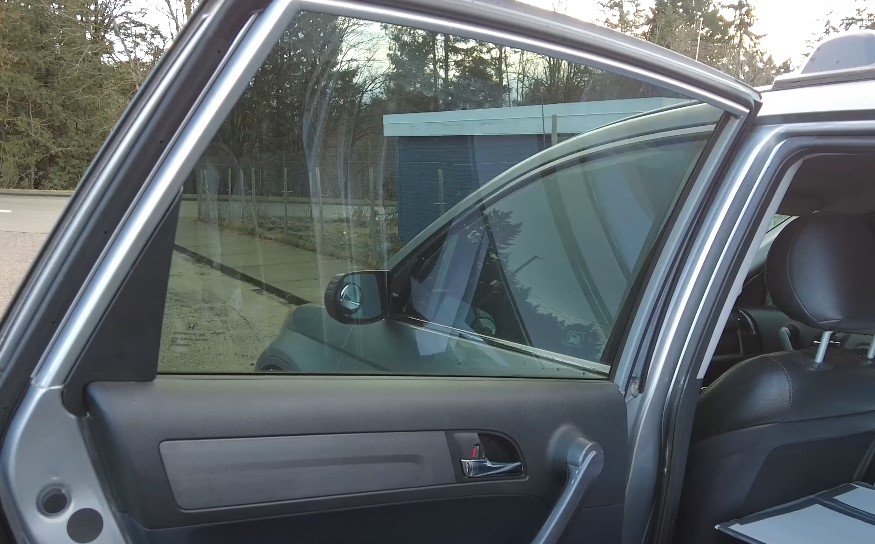 Close-up of a car door, highlighting the window's reflective surface and the door's trim