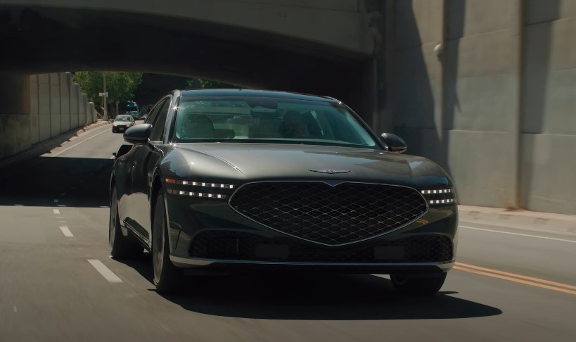 Sleek dark gray Genesis G90 model navigates an urban underpass