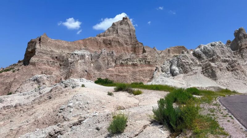 Jagged rock formations and desert terrain under a clear blue sky at Badlands National Park in South Dakota.