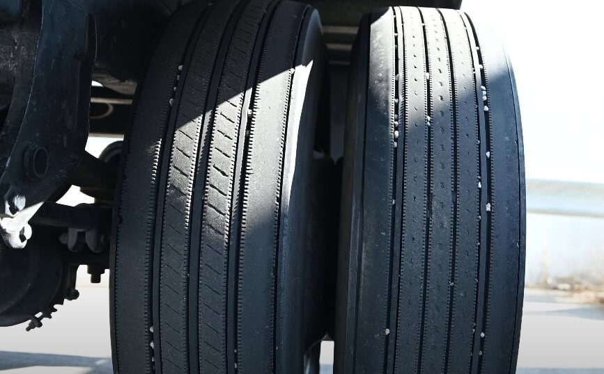 Close-up view of two truck tires, showcasing the tread patterns and varying degrees of wear