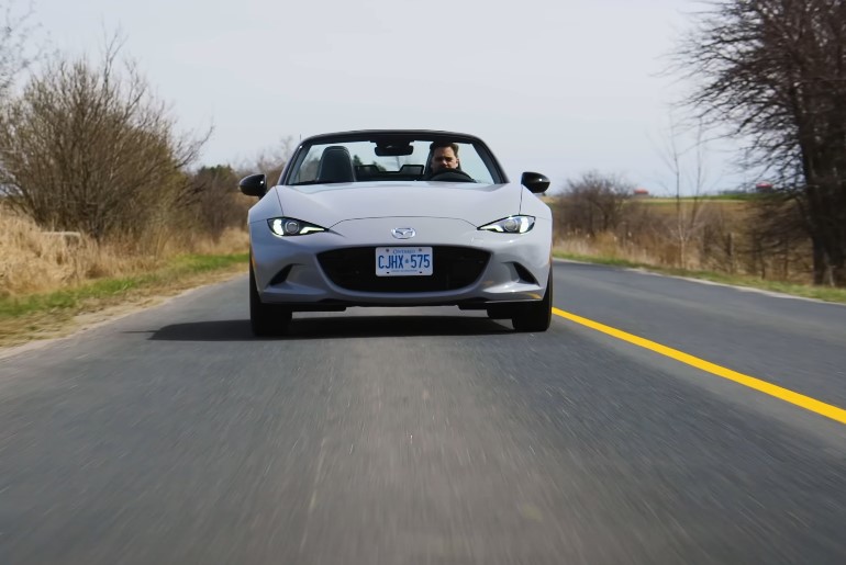 Man driving white Mazda Miata roadster on a paved road