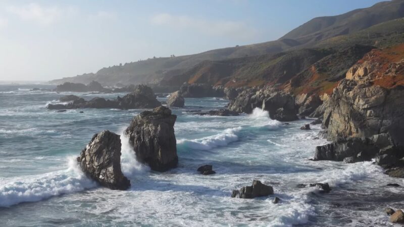 Waves crashing against rugged sea cliffs along Big Sur’s coastline on the Pacific Coast Highway in California