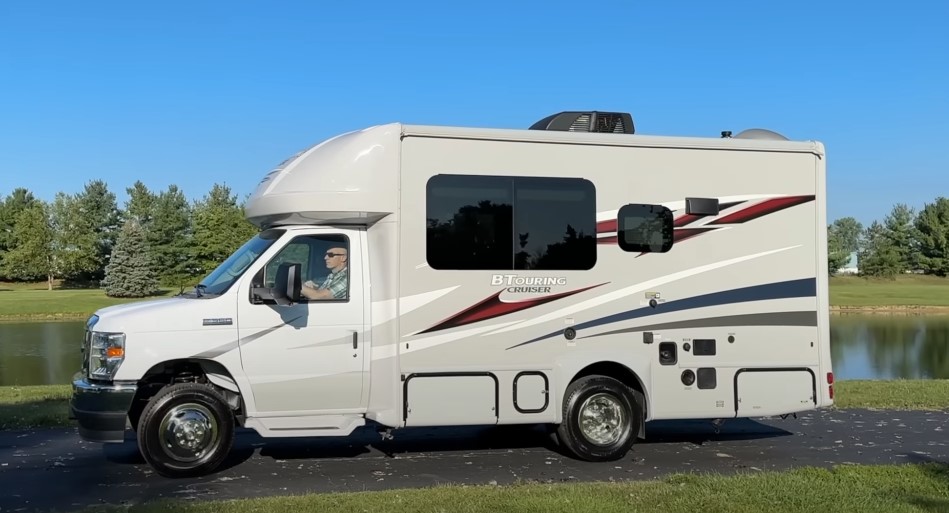 A gleaming white van, a gray camper atop, ready for a scenic journey