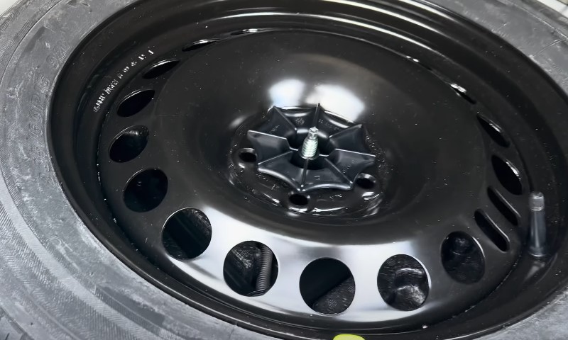 A black tire with multiple holes and a matching black rim