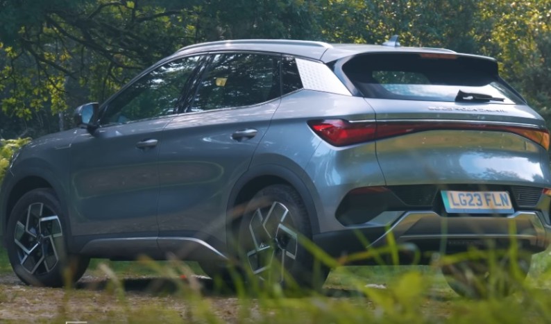 Gray electric crossover surrounded by grass and trees