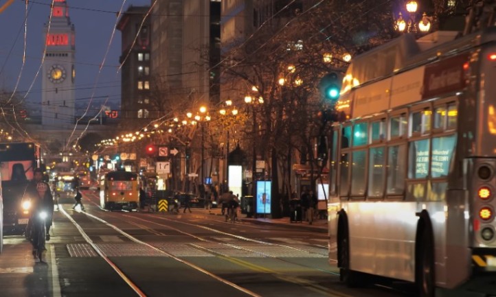 A bustling city street featuring a bus and a prominent clock tower in the background