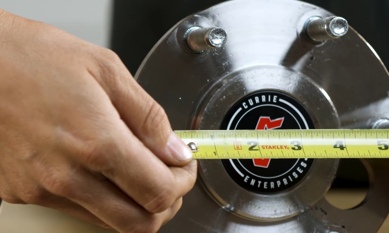 Person measures bolt pattern using a meter