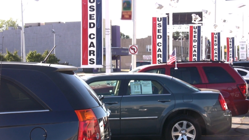 A row of used cars displayed on a lot with tall โUsed Carsโ banners in the background