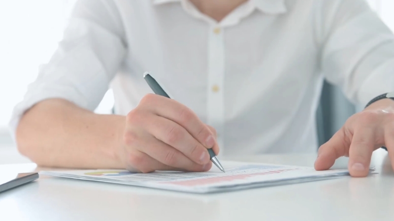A person reviews paperwork and writes notes while planning business finances