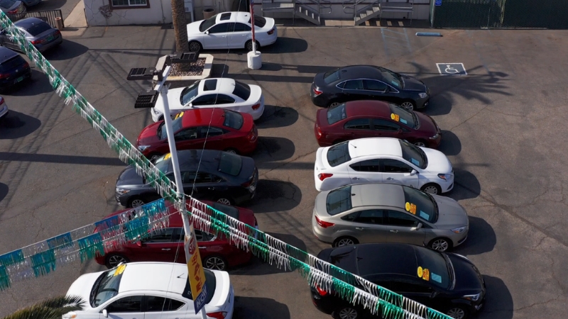 A small used car lot with tightly parked sedans displayed for sale