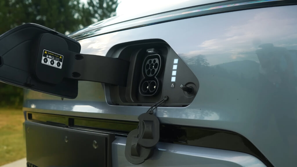 Close-up of an electric car charging inlet with open flap, showing connector ports ready for fast charging in a public setting