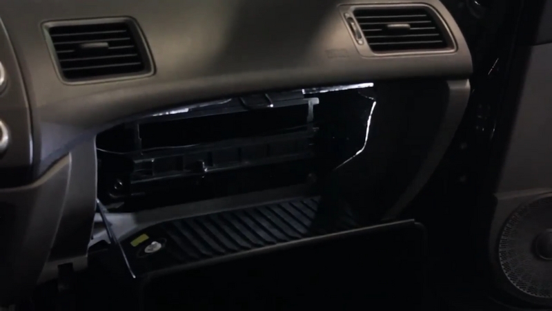 The glovebox sits open as the cabin air filter housing is exposed for replacement