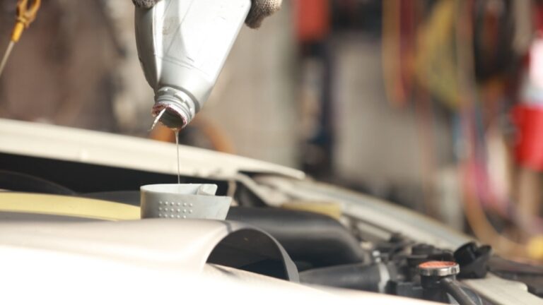 Oil pours into an engine through a small funnel during basic car maintenance tasks